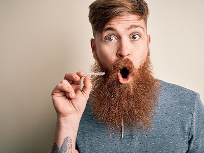 A surprised man holding a damaged Invisalign aligner