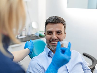 A dentist showing her patient an Invisalign aligner