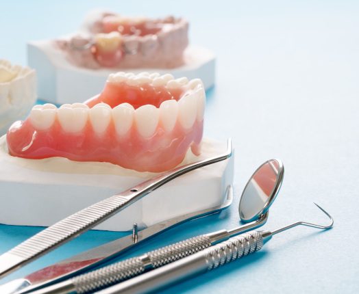 A closeup of complete or full dentures against a blue background