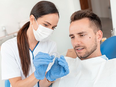 A dentist showing an Invisalign tray to her patient