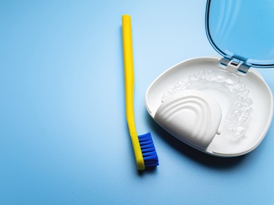 Transparent aligners in a case next to a toothbrush