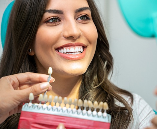 A dentist comparing a patient’s smile with a shade guide