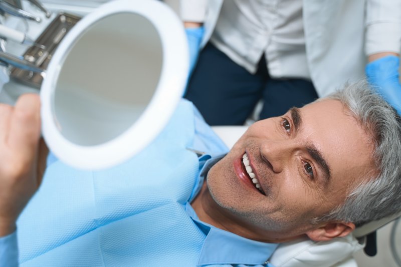 A man admiring his new dental veneers in a mirror